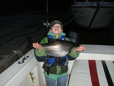 young boy holding king salmon at night